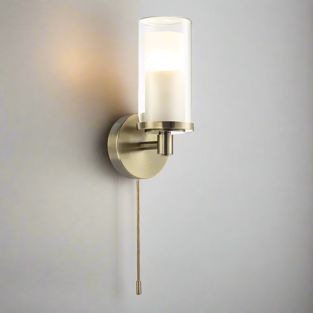 Brass wall sconce with a clear glass shade on a white background