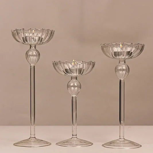 A set of three transparent glass candle holders of varying sizes, with a sleek design, displayed against a neutral background.