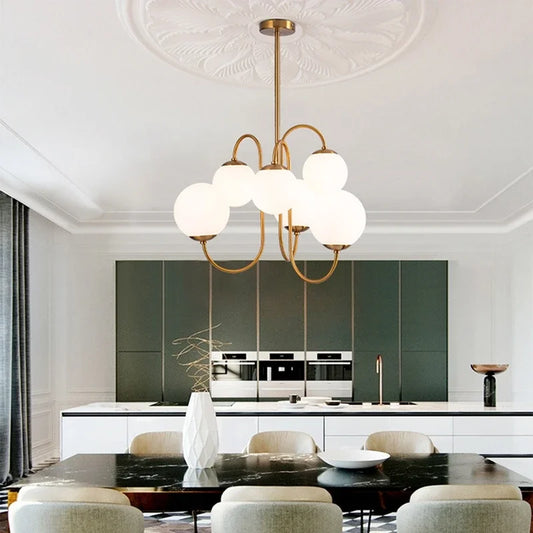 A Modern Scandi Opal LED 6 Arms Glass Ball Pendant Chandelier hanging over a dining table, with a brushed nickel finish and white glass shades.