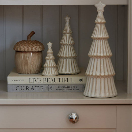 Decorative items including trees and a candle on a shelf with a neutral background