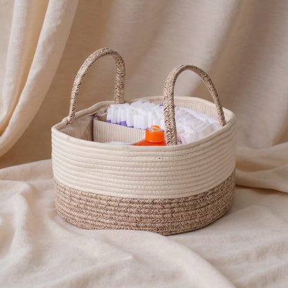 Woven basket with handles containing baby items on a beige fabric background