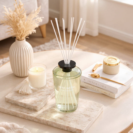 Green diffuser on a coffee table with candles and books in a cozy living room.