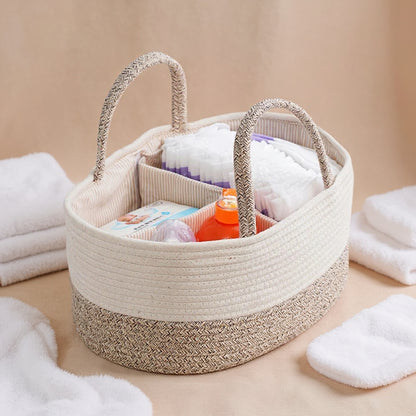 Woven storage basket with handles filled with baby items on a beige surface