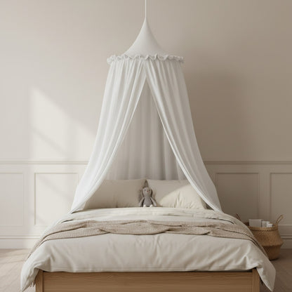 A white fabric canopy bed cover draped over a wooden bed frame with cream bedding, set in a softly lit, minimalist bedroom.