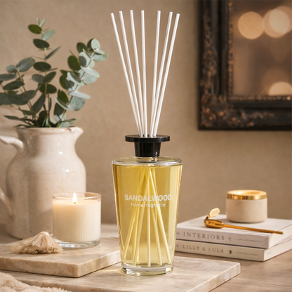 Sandalwood diffuser bottle on a table with candles and books in the background
