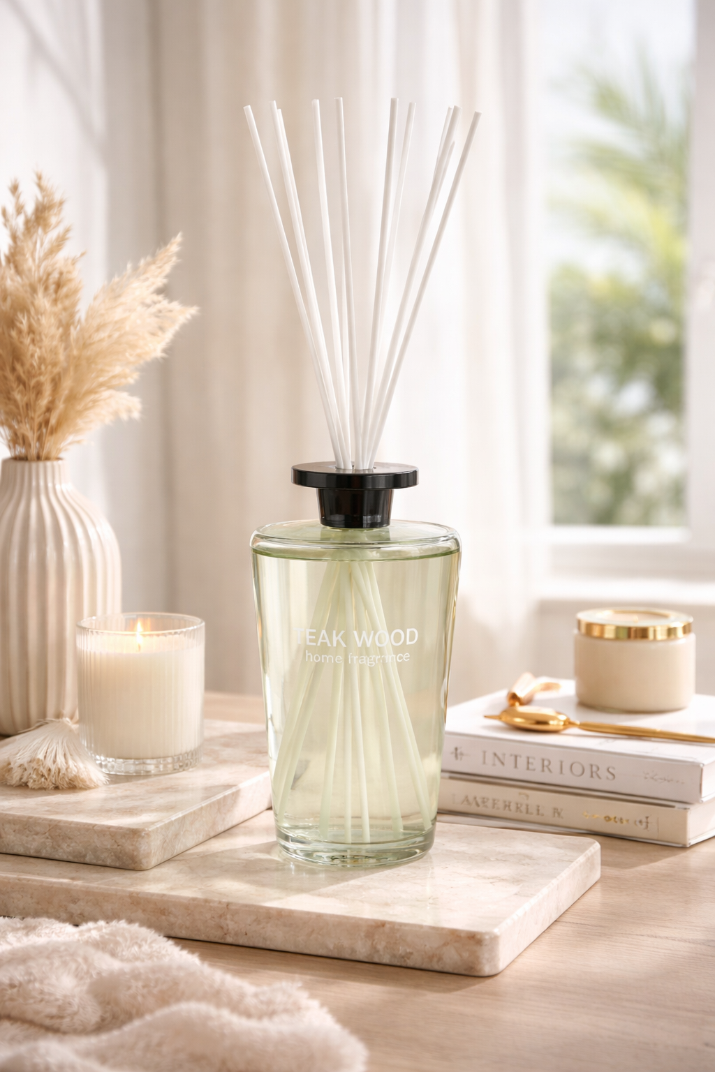 Decorative diffuser with reeds on a marble surface with candles and books in the background.