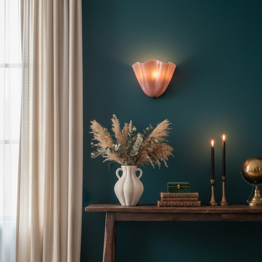 Room interior with a dark green wall, wooden console table, vase with dried plants, and wall sconce.