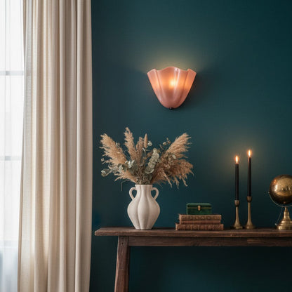 Room interior with a dark green wall, wooden console table, vase with dried plants, and wall sconce.