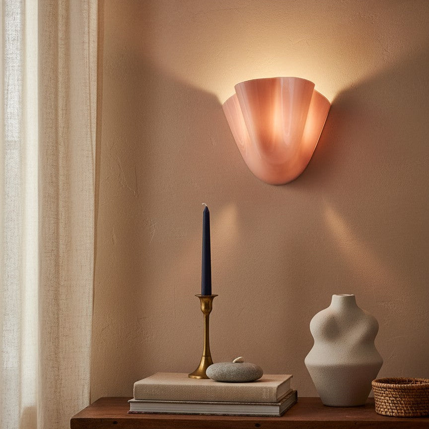 Copper wall sconce casting a warm glow on a wooden table with decorative items.