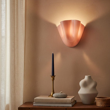 Copper wall sconce casting a warm glow on a wooden table with decorative items.