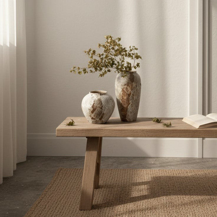 Two vases with plants on a wooden table in a minimalistic room.