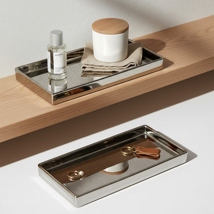 Two metallic trays with a bottle, candle, and key on a wooden surface.