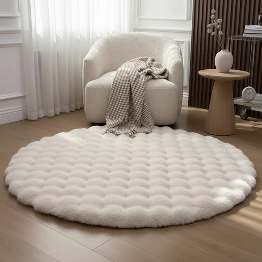 Round white fur rug on a wooden floor with a chair and side table in the background.