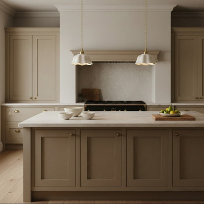 A modern kitchen interior with a large central island in taupe, matching upper and lower cabinets, white marble countertops, two white pendant lights, a stone backsplash, and light wood flooring.