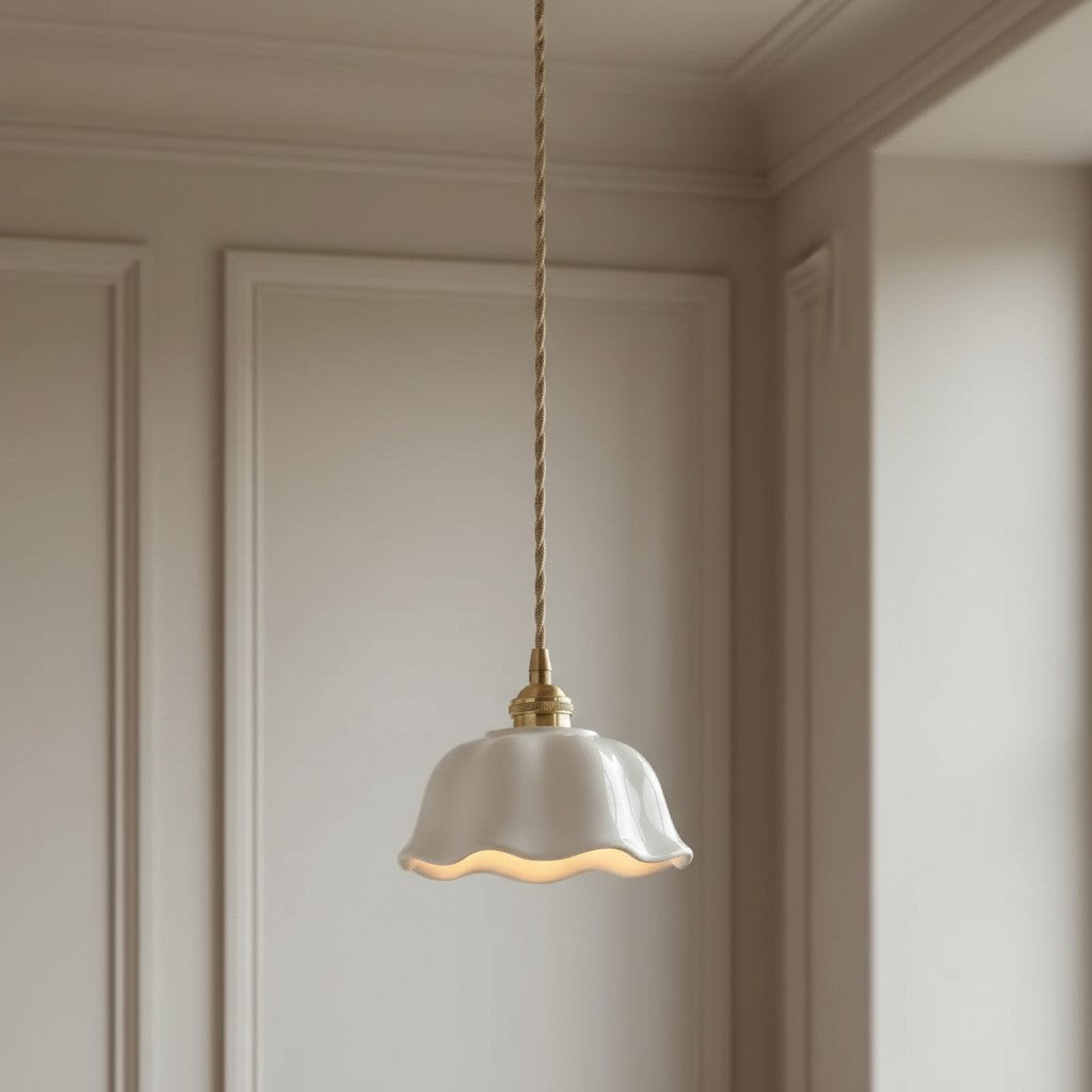 A single pendant light with a white fluted glass shade and a brass-toned cord and cap, hanging in a neutral cream-colored room with decorative paneling.