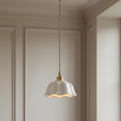 A single pendant light with a white fluted glass shade and a brass-toned cord and cap, hanging in a neutral cream-colored room with decorative paneling.