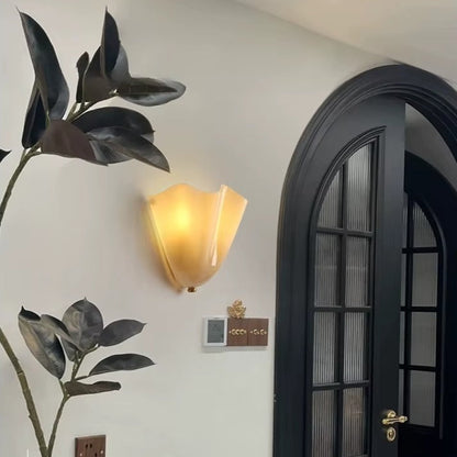 Decorative wall light fixture on a white wall next to a black door.
